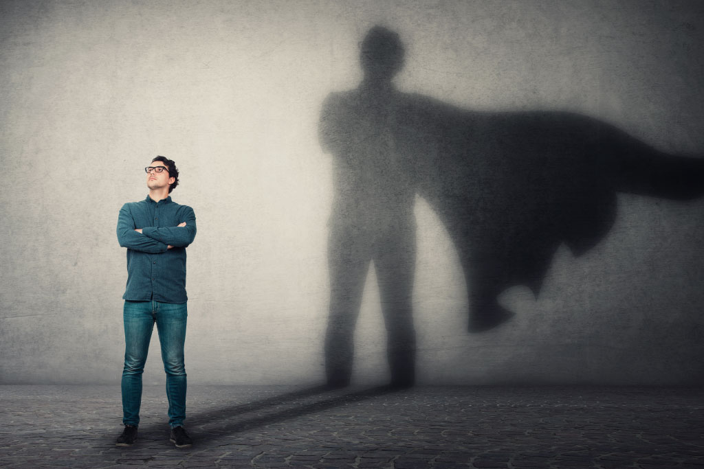 Man Standing In Front Of Wall With His Shadow Having A Cape