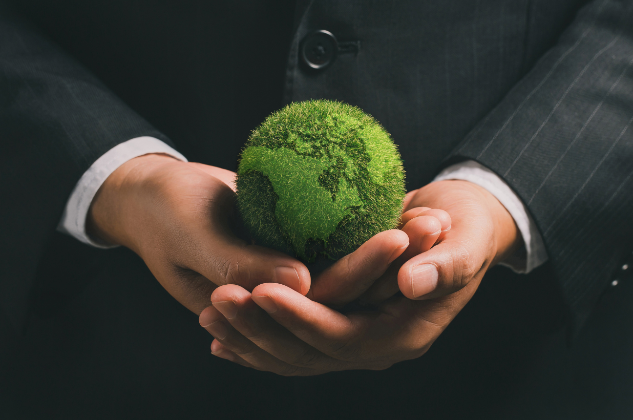 the torso and hands of a man in business attire holding a globe made of grass, visualizing innovative CSR companies